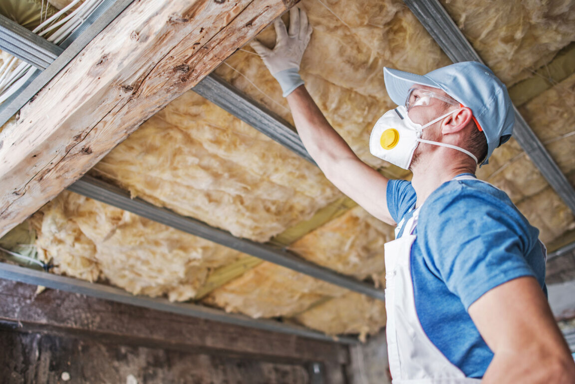 man installing batt fiberglass insulation