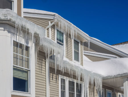 ice-dam-white icicles on the eave of a white home