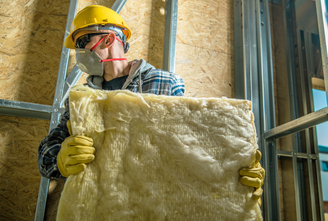 worker installing batt insulation in a home