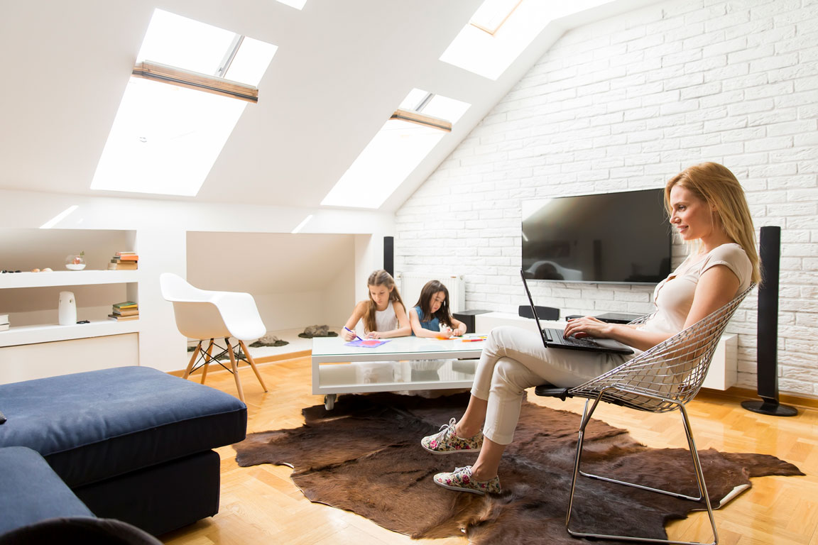 woman sitting on her laptop in the attic with her two daughters