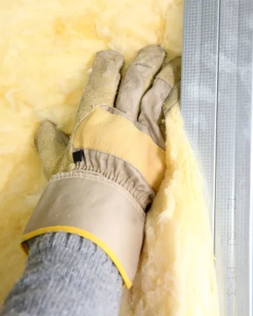 RID blog 3 fiberglass-insulation-installation (1) Gloved hand installing fiberglass